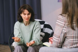 Dialectical Behaviour Therapy Certification - Calm female sitting on armchair and giving interview to concentrated woman in light room