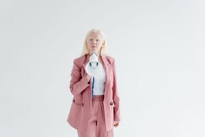 The Power of Influence & Motivating People to Buy Certification - Portrait of a confident woman in a pink suit holding a megaphone on a white background, promoting leadership and empowerment.