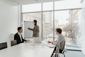 Leading Team Meetings Certification - Three professionals engaged in a business meeting in a bright conference room.