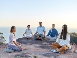 Mindfulness Certification - Five adults meditating outdoors on a mountain top during sunrise, promoting relaxation and mindfulness.