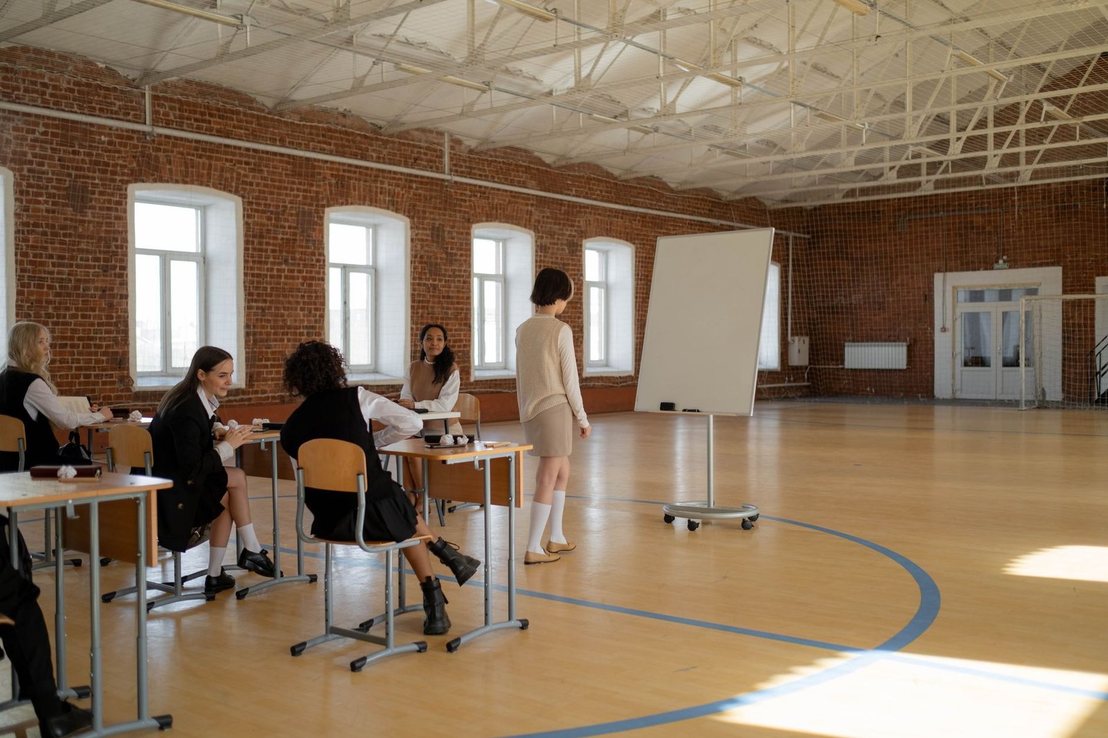 Safeguarding for Students Certification - Students in school uniforms engaged in a lesson with a teacher in a spacious classroom.