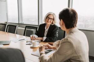 Communication Techniques for Managers Certification - Two businesswomen in discussion during a meeting in a modern office setting.