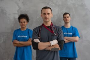 Professional Boundaries in Health and Social Care Certification - Healthcare worker with stethoscope and volunteers standing in solidarity indoors.