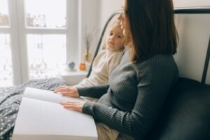 Safeguarding Children Certification (Including Disabilities) - A woman and child reading a braille book in a cozy bedroom setting, enhancing child development.