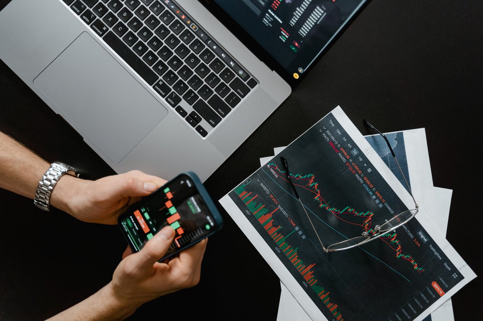 Digital Marketing Certification Level 2 - Hands using smartphone beside laptop with stock charts, showcasing digital trading.