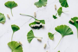 Memory Enhancement Certification - Flat lay of ginkgo leaves with memory capsules on marble surface.