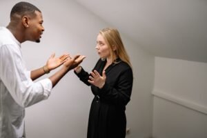 Handling Conflict in High-Value Relationships Certification - A man and woman having a heated discussion in a minimalistic indoor space.
