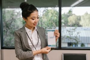 Developing a Compensation & Benefits Package Certification - Young professional woman holding a conference program brochure indoors.