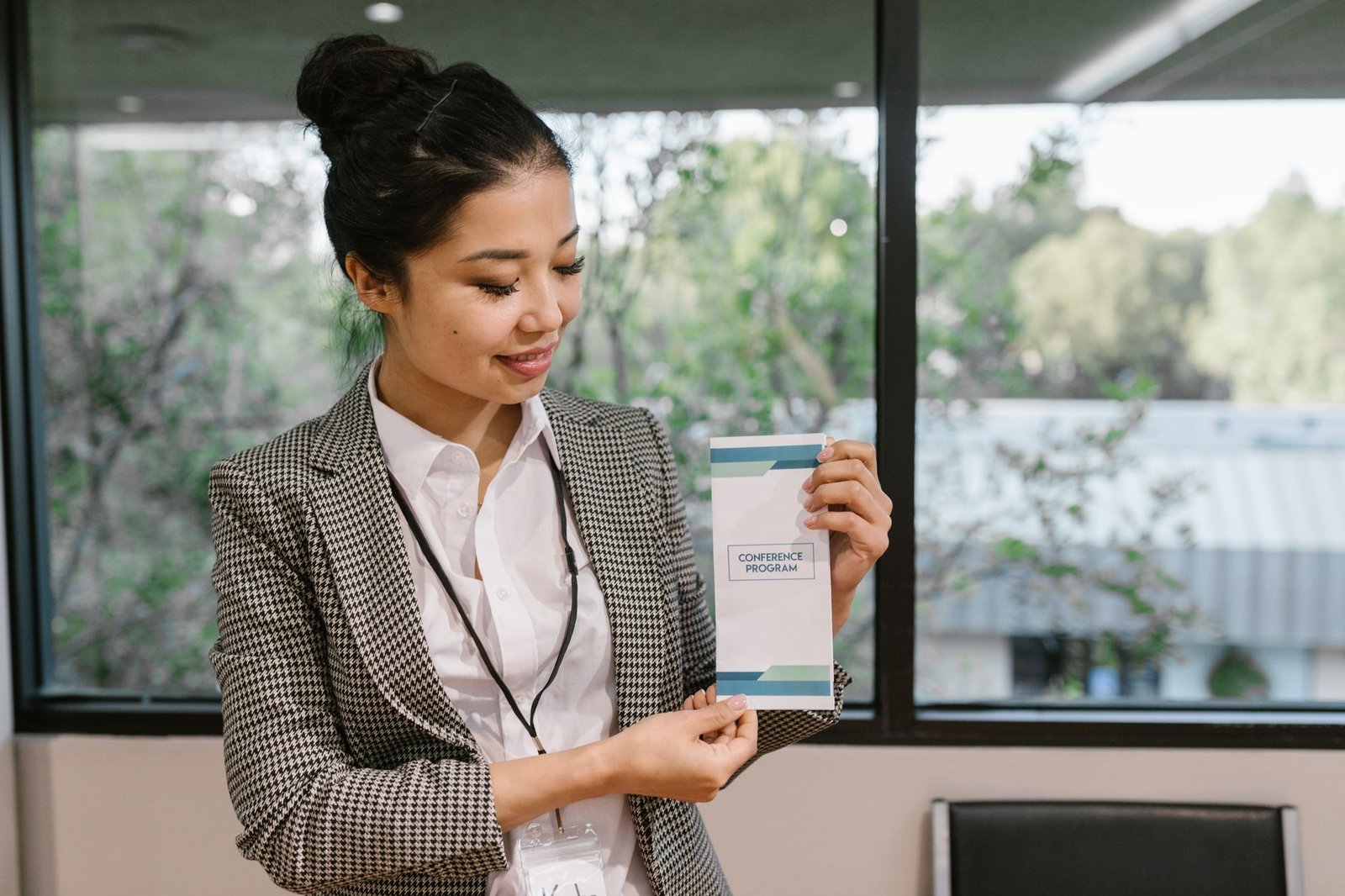 Developing a Compensation & Benefits Package Certification - Young professional woman holding a conference program brochure indoors.