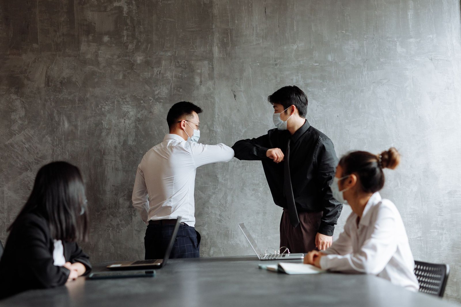 Office Etiquette Certification - Business colleagues greet with elbows in an office, adhering to health protocols.