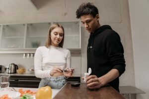Diabetes Awareness Certification - A young couple in a kitchen setting measuring blood sugar levels with a glucometer