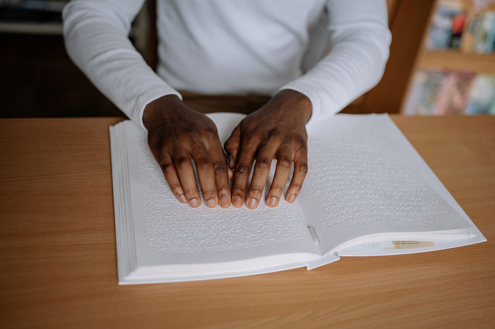 Learning Disabilities Awareness Certification - A person reading a Braille book indoors, focusing on accessibility and disability inclusion.
