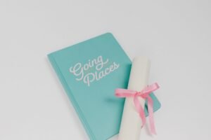 Romantic Writing Diploma - Teal notebook labeled 'Going Places' with a diploma wrapped in pink ribbon on a white surface.