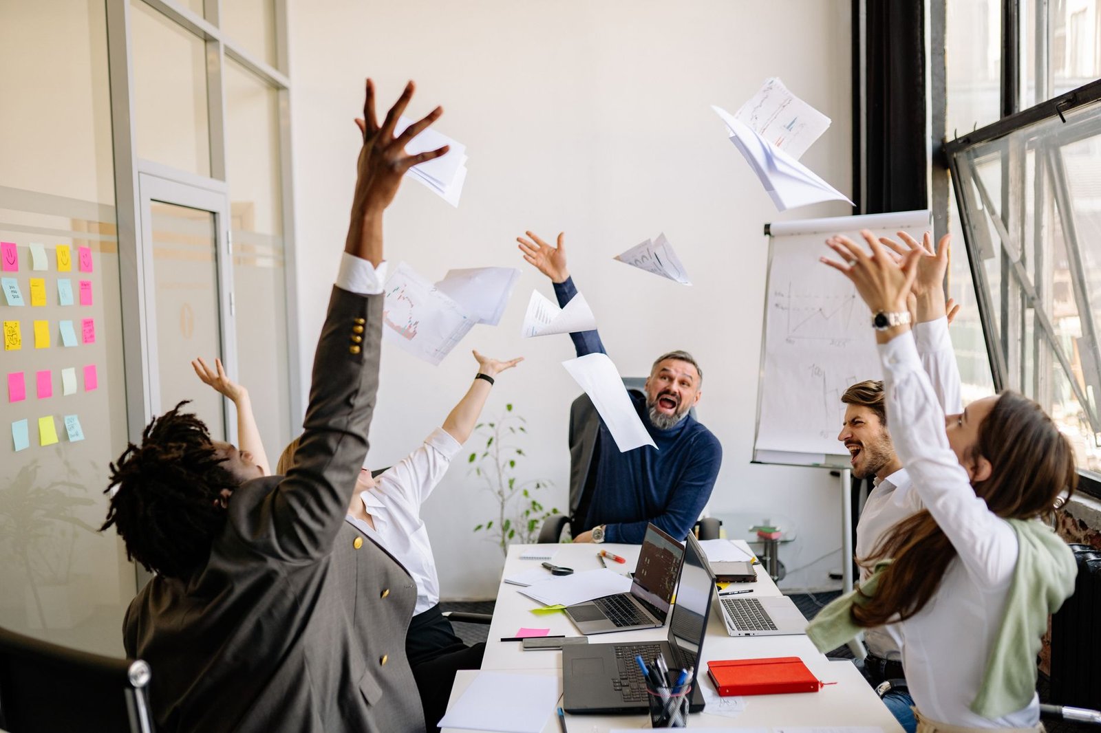 Employee Motivation Certification - A diverse office team celebrating with papers in the air, showing teamwork and success.