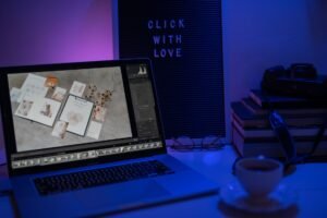 Think Before You Click 2 - A stylish workspace featuring a laptop, camera, and books under soft blue lighting.