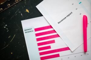 Writing Sales Proposals Certification - Close-up of market research charts and a revenue report with a pink pen on a desk.
