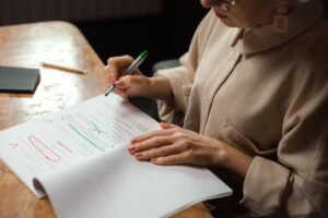 Proofreading Basics Certification - Close-up of a senior woman editing a manuscript at a desk with a green marker indoors.