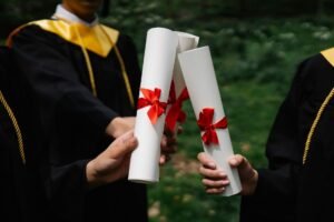 British Citizenship Diploma - Group of graduates holding diplomas with red ribbons during a ceremony outdoors.