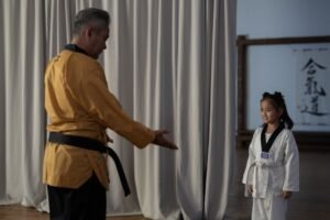 Master Talking to Anyone Certification - Young girl in karate gi with instructor. Martial arts training in dojo.