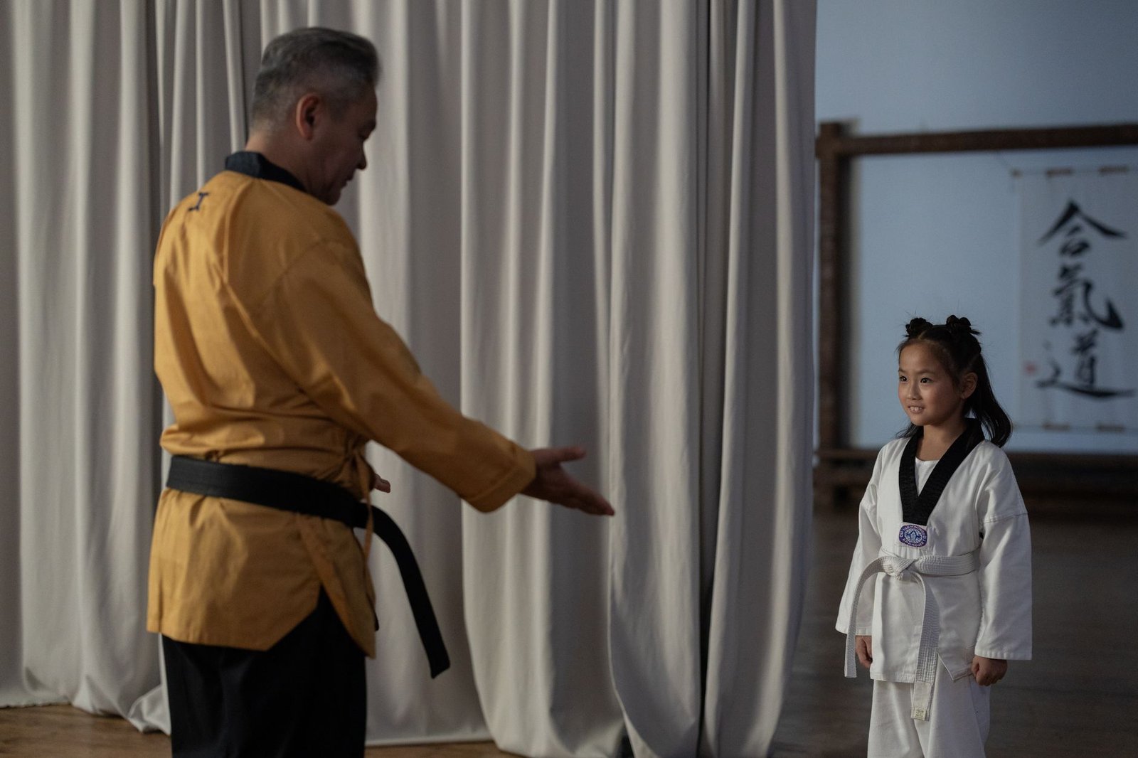 Master Talking to Anyone Certification - Young girl in karate gi with instructor. Martial arts training in dojo.