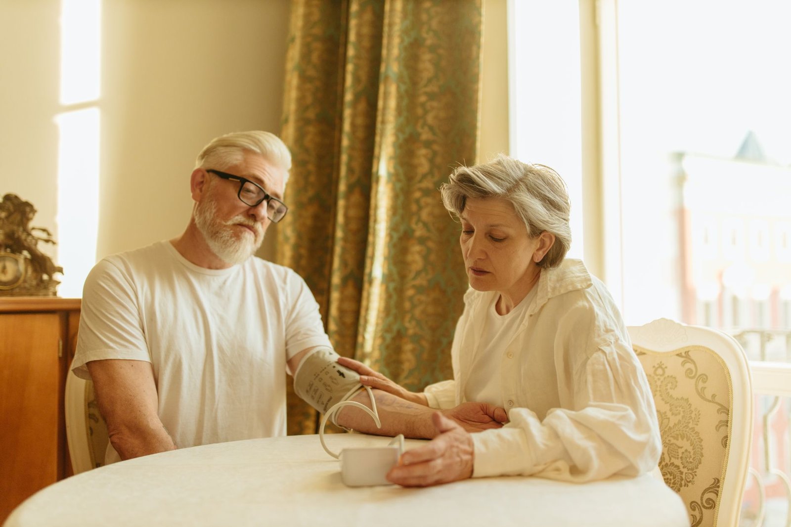 Domiciliary Care Certification - An elderly couple at home measuring blood pressure with a digital monitor, depicting care and health awareness.
