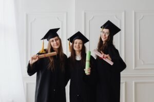 Nutrition Diploma - Three women in graduation gowns celebrating their academic achievements with diplomas.