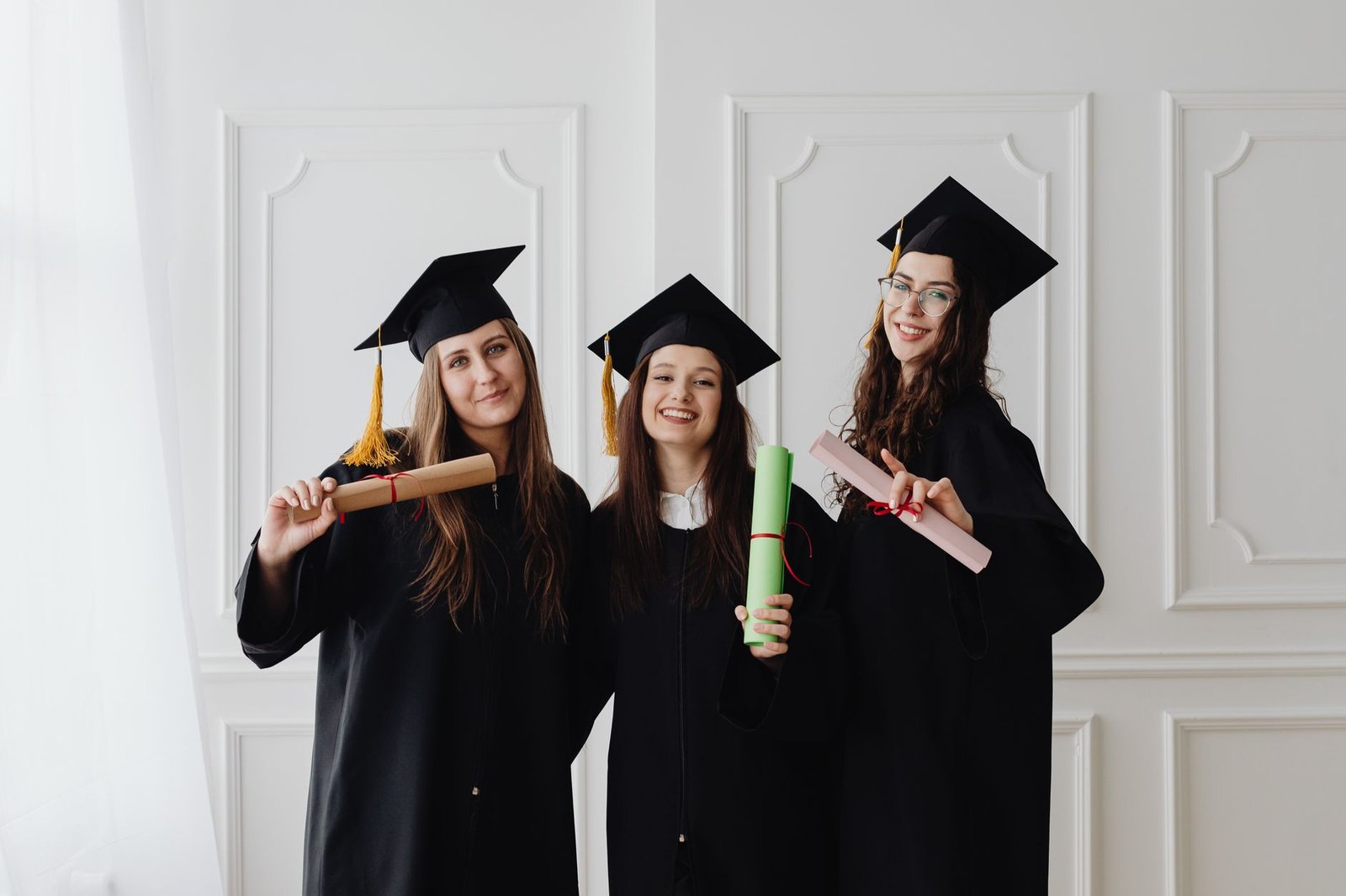 Nutrition Diploma - Three women in graduation gowns celebrating their academic achievements with diplomas.