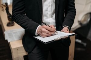 UK Employment Law Certification - Business professional signing a contract on a clipboard at the office.