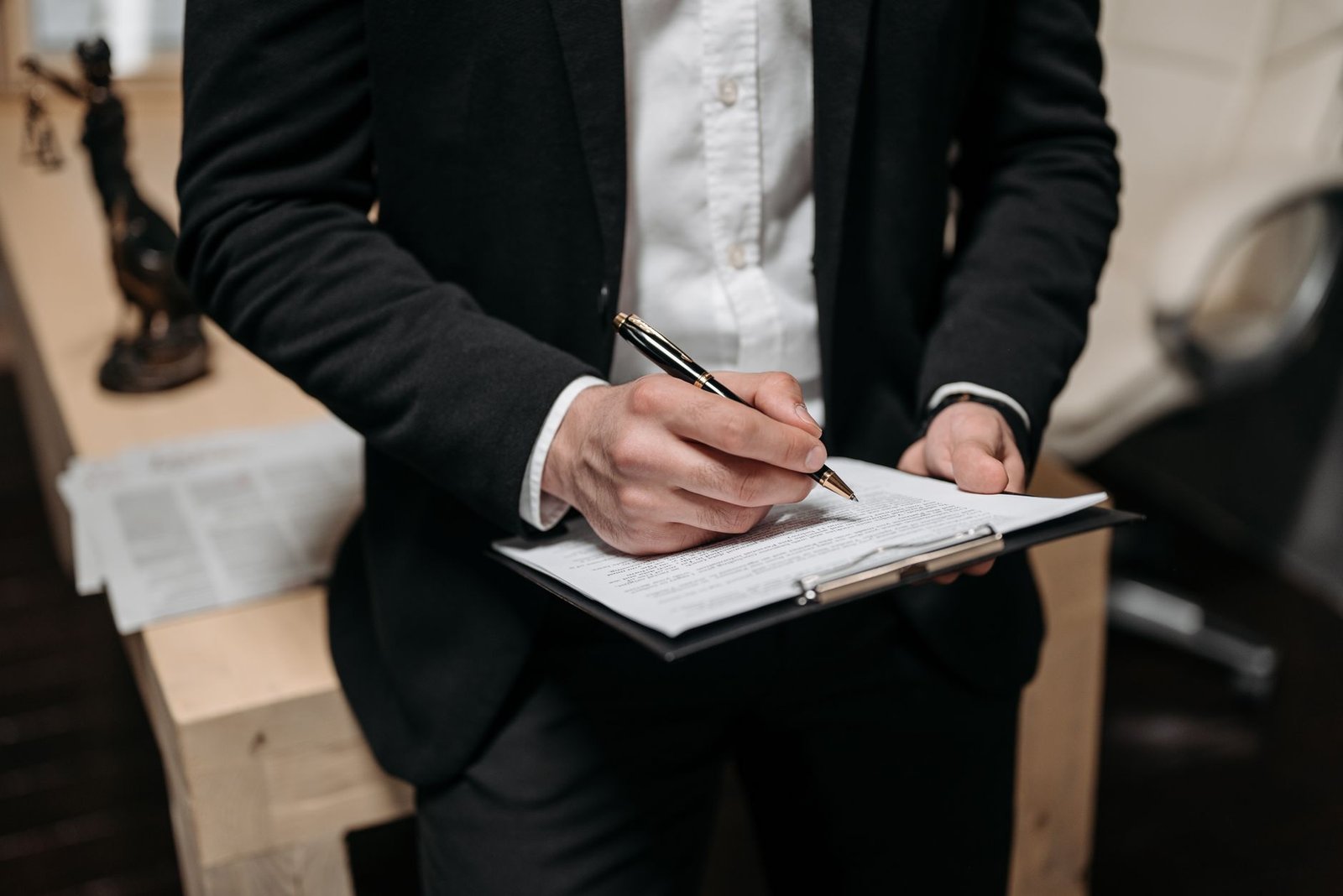 UK Employment Law Certification - Business professional signing a contract on a clipboard at the office.