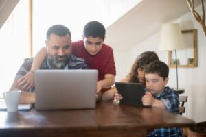 Safeguarding Children Including Internet Safety Certification - Father and kids engaging with a laptop and tablet in a cozy home setting.