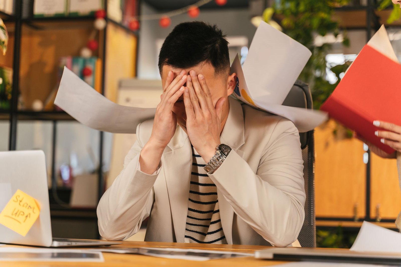 Stress Management In the Workplace Certification - Stressed businessman overwhelmed by paperwork in office environment, demonstrating burnout.