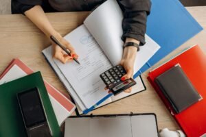 Finance for Non-Finance Managers Certification - Accountant analyzing financial documents with a calculator on a desk, highlighting business tasks.