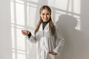 Holistic Health Practitioner Certification - Asian acupuncturist holding a ventosa glass cup, smiling in a white coat, indoors.