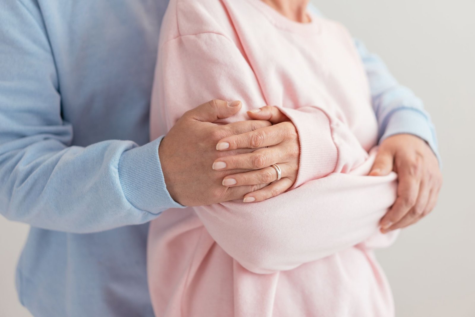 Safeguarding Adults Certification - A tender embrace captured in a close-up, displaying affection with hands wrapped in pastel sweaters.