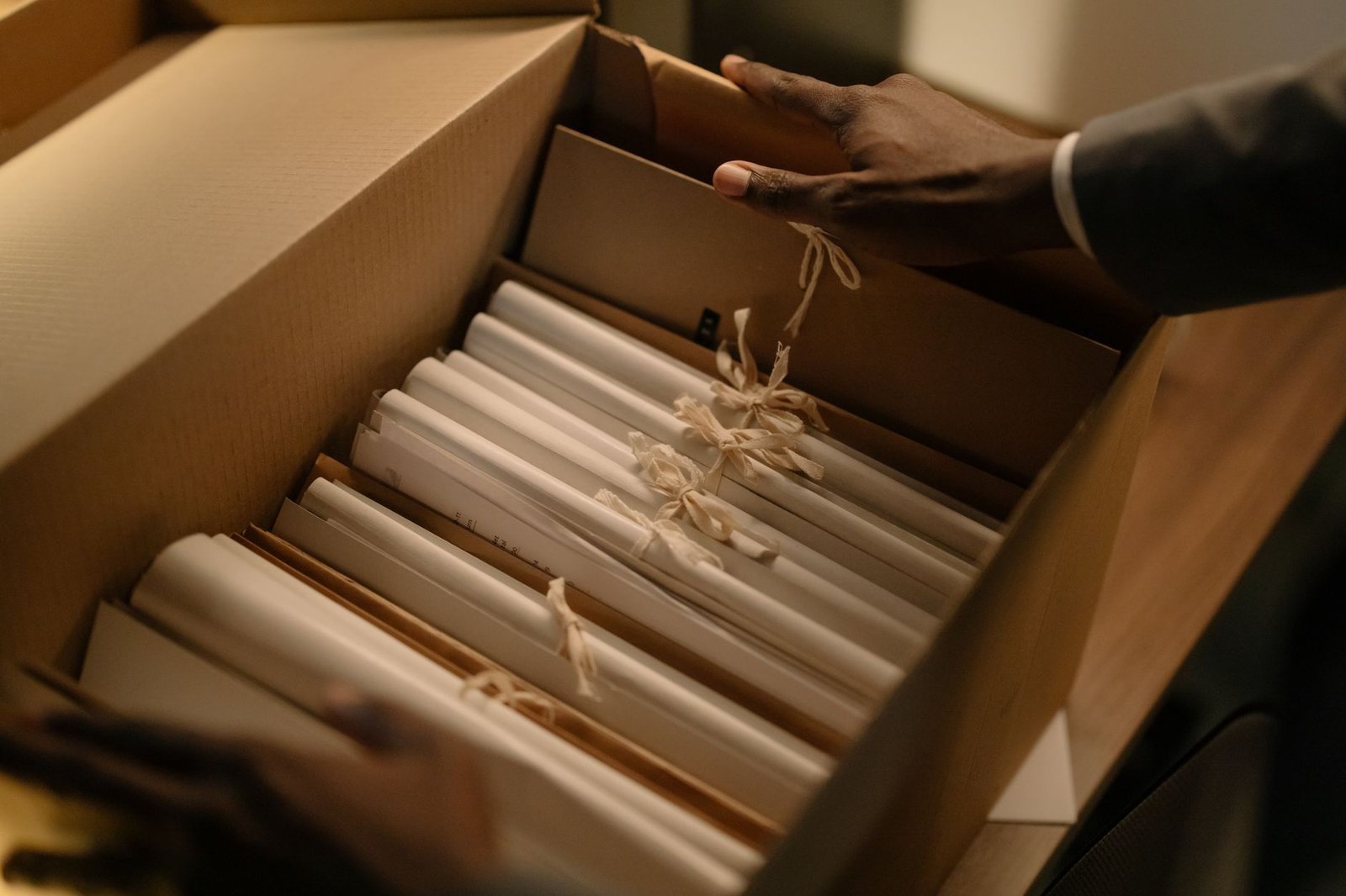 HR: Protecting Confidentiality Certification - Hands organizing files in a box, symbolizing investigation and research.