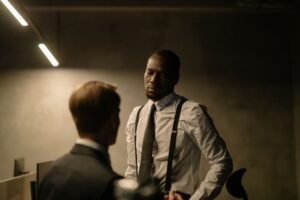 Conducting Employee Appraisals Certification - Two men in formal attire having a serious discussion in a dimly lit office with modern decor.