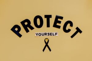 Sexual Harassment Prevention & Reasonable Steps - Conceptual awareness image with "Protect Yourself" text and black ribbon on yellow background.