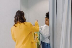 Fitting Room Advice Certification - A personal stylist helps a client with clothing choices in a fitting room, focusing on fashion styling.