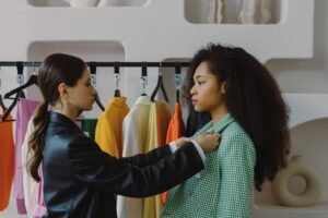 Becoming a Personal Stylist Certification - Fashion stylist adjusts outfit for model in chic boutique.