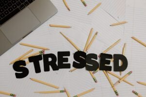 Managing Your Workload Certification - Overhead view of a stressed workplace setup with broken pencils scattered around a laptop.