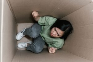 Rescuing Difficult Customers Certification - A woman feeling trapped and anxious inside a small cardboard box, symbolizing claustrophobia.