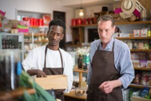 Professional Retail Management Certification - Two male employees organizing products in a cozy grocery store.