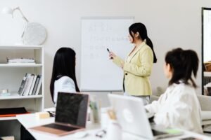 Presentation Skills Certification - Women in an office presenting business strategy using a whiteboard.