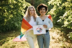 Is the Customer Always Right Certification - A loving couple embraces pride with a rainbow flag in a serene outdoor setting.
