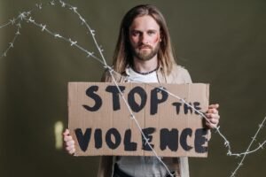 Dealing with Workplace Violence Certification - Man holding a 'Stop the Violence' sign with barbed wire emphasizing peace and protest.