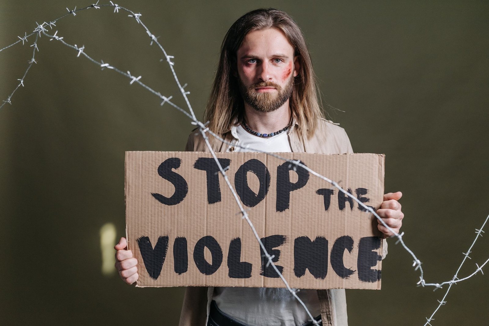 Dealing with Workplace Violence Certification - Man holding a 'Stop the Violence' sign with barbed wire emphasizing peace and protest.