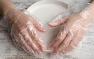 Food Safety Level 4 Certification - Close-up of hands wearing plastic gloves on a plate, highlighting hygiene and protection.