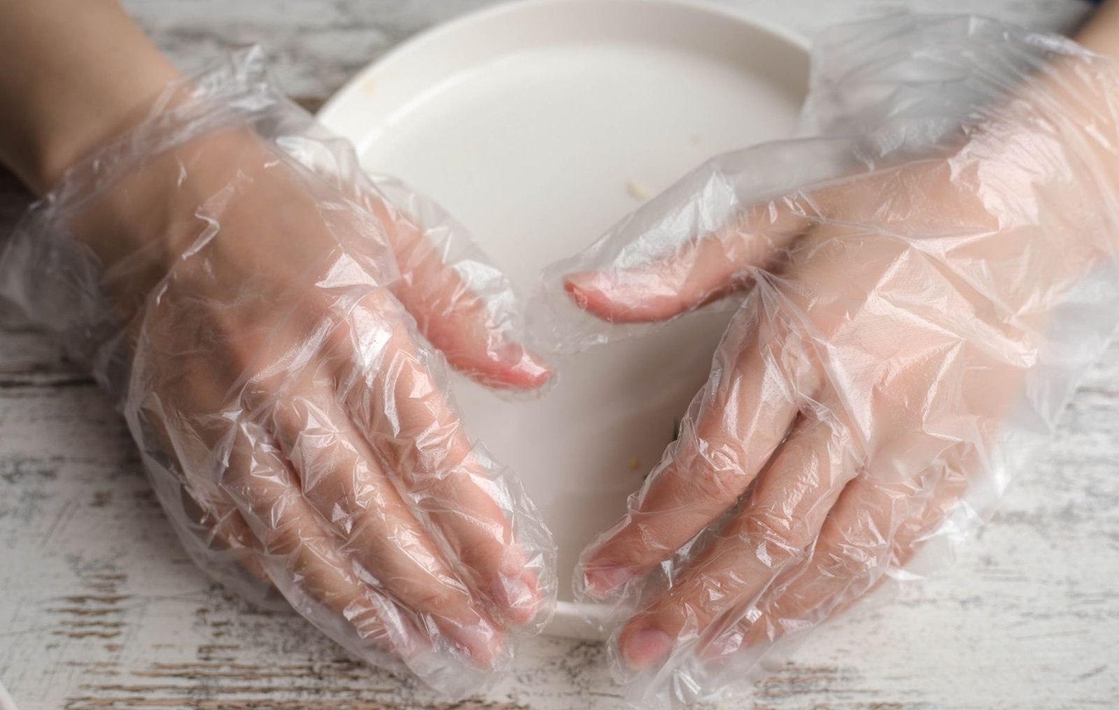 Food Safety Level 4 Certification - Close-up of hands wearing plastic gloves on a plate, highlighting hygiene and protection.