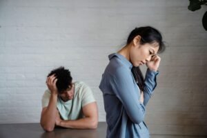 Conflict in the Workplace Certification - An Asian woman and man feeling misunderstood and frustrated in a relationship indoors.