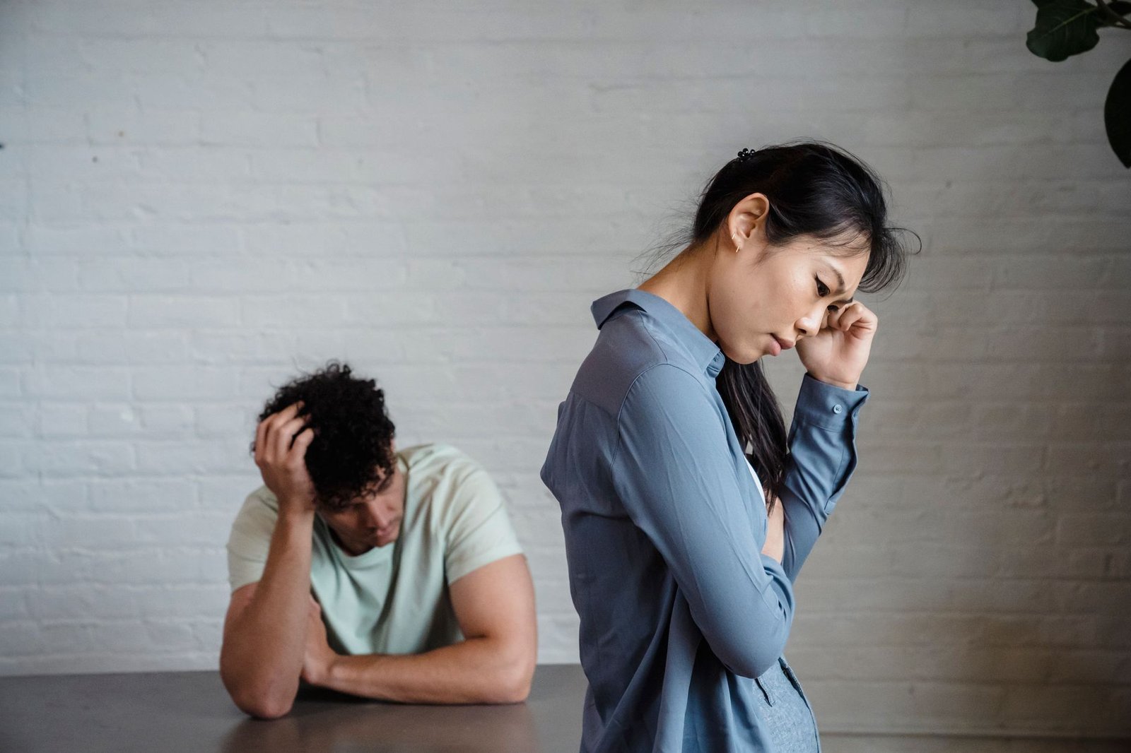 Conflict in the Workplace Certification - An Asian woman and man feeling misunderstood and frustrated in a relationship indoors.